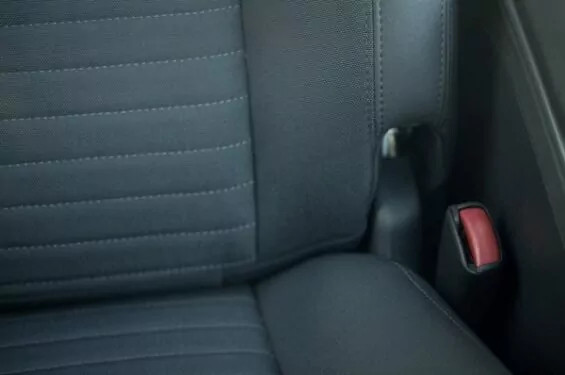 Close-up of a person's hands repairing a tear in car upholstery with needle and thread