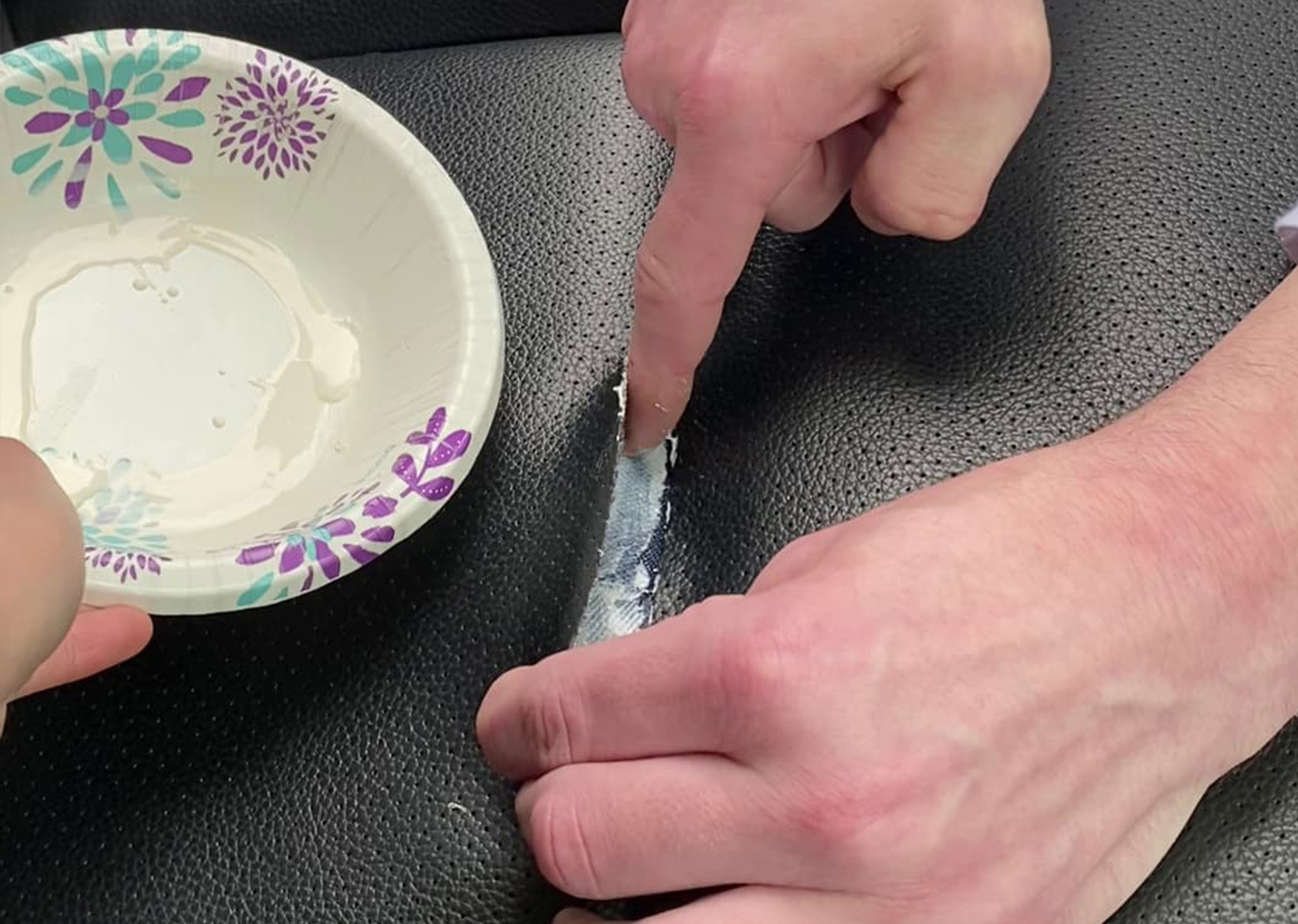 Applying leather adhesive with a finger to repair a torn car seat