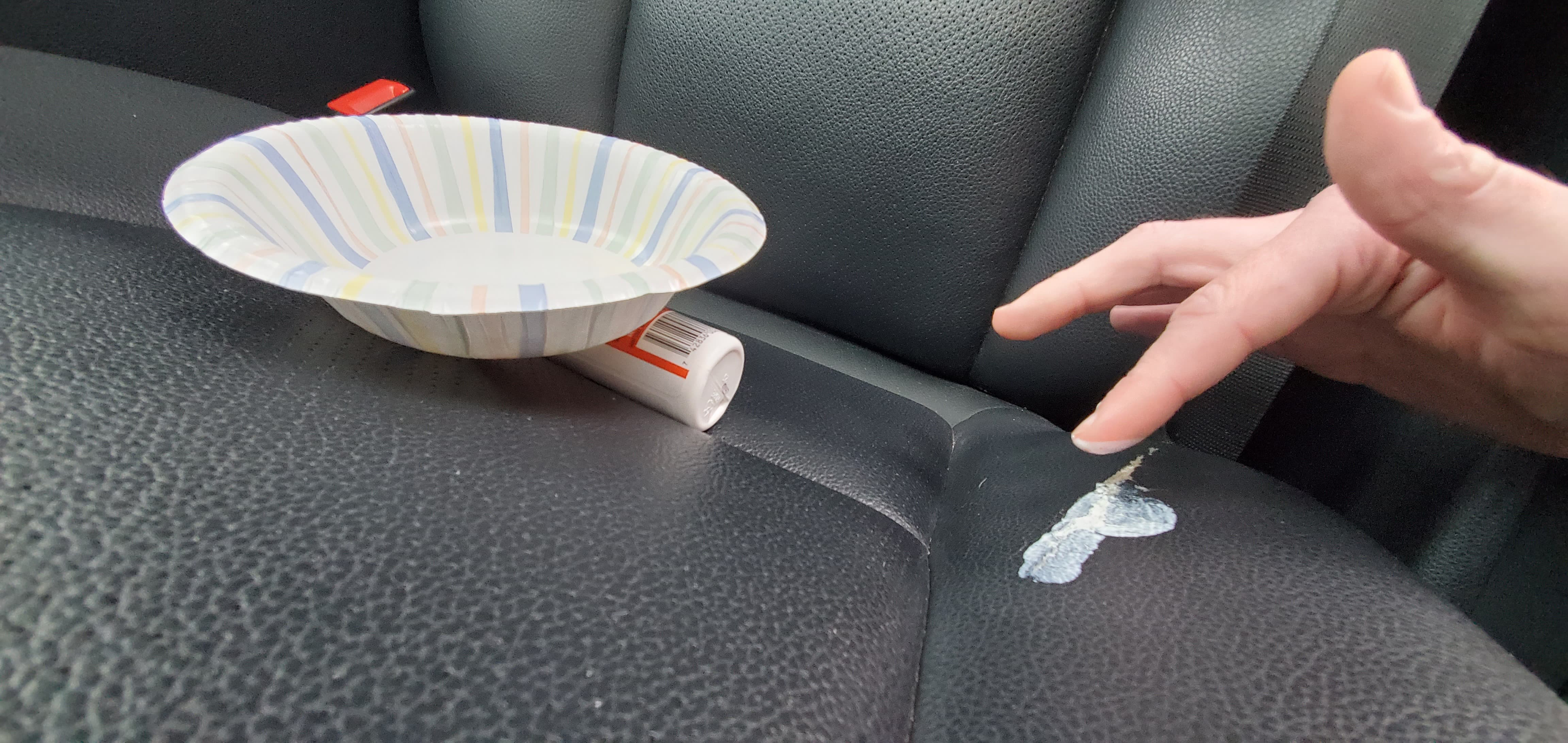 Using a finger to apply leather adhesive into cracks of a car seat