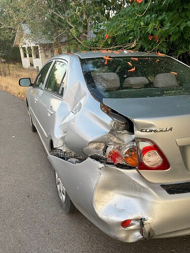 Rear and side damage to a Toyota Corolla after a car accident, highlighting the smashed trunk and dented side panel, relevant to insurance claim assessment.