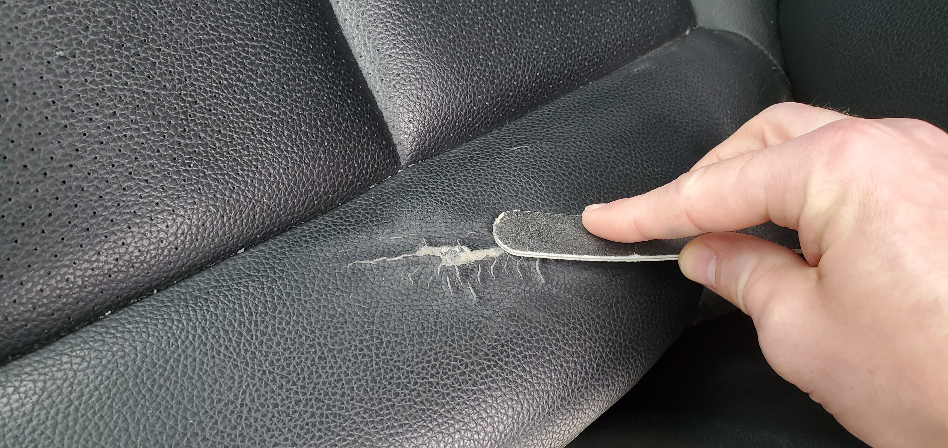 Using an emery board to smooth the surface of a repaired car seat tear