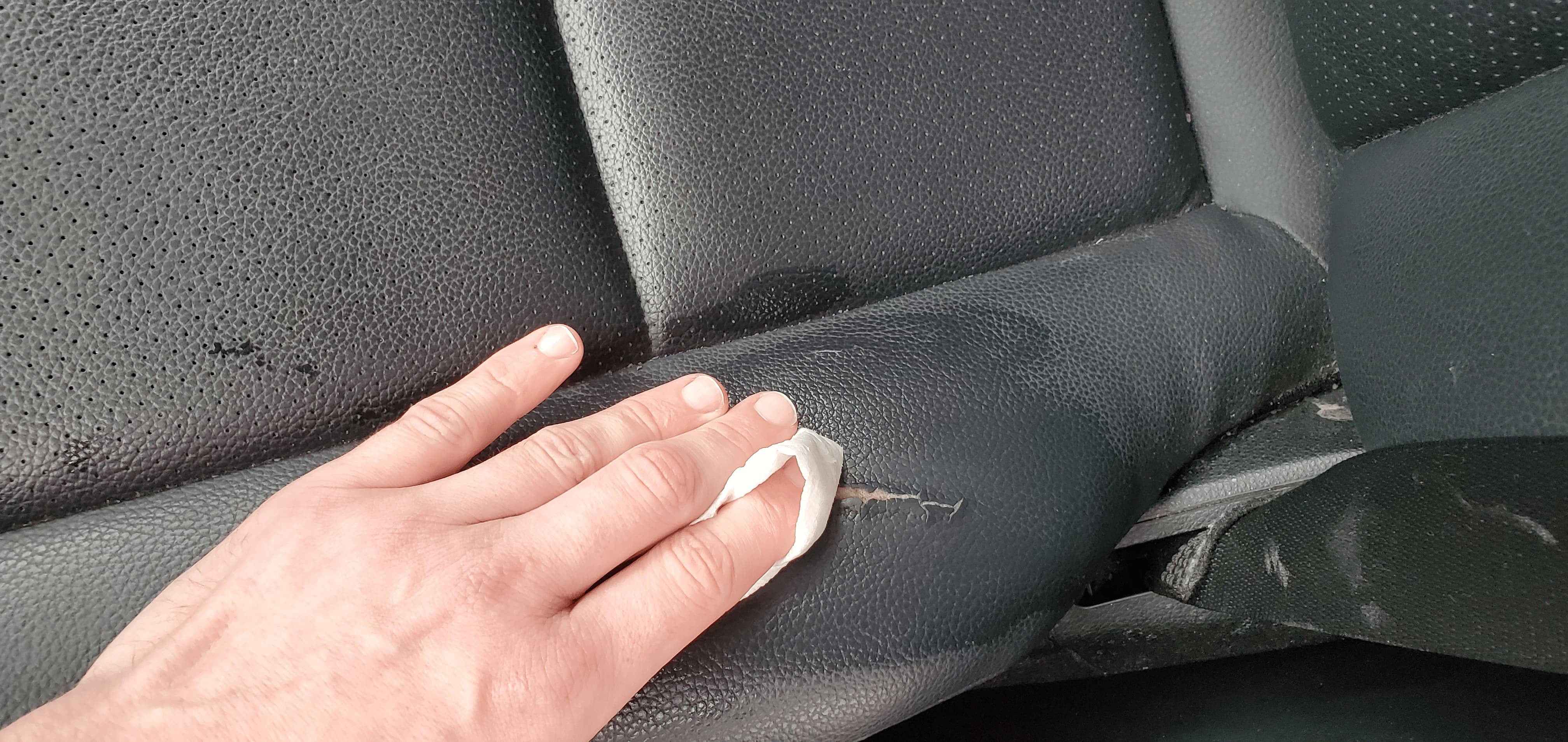 Cleaning a car seat tear with alcohol wipe before color application