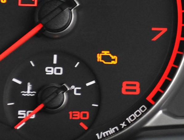 Car dashboard illuminated with engine management light and other warning symbols indicating limp mode.