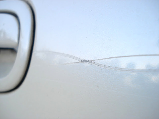 Car scratch extending from door to rear panel, showing depth and severity.