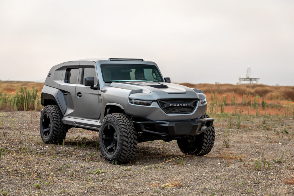 Rezvani Tank marketed as EMP-proof, alt text: A black Rezvani Tank, an SUV marketed as EMP-proof, parked on a paved surface with desert landscape in the background, highlighting its rugged and imposing design.