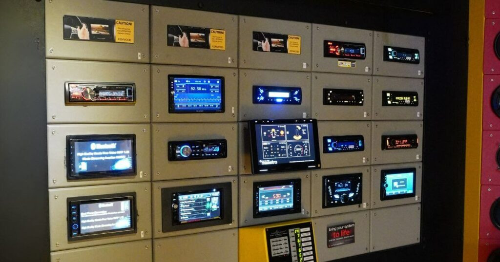 A display wall showcasing various car head units at TAS Electronics, highlighting the range of options for car audio systems.