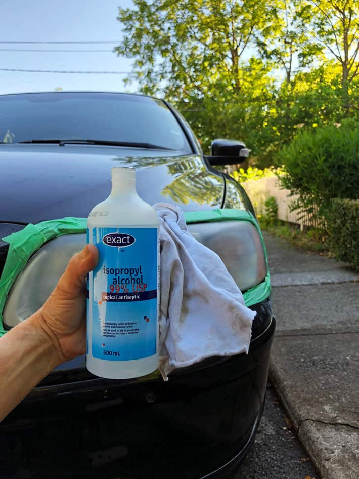 A bottle of isopropyl alcohol with a car headlight in the background.