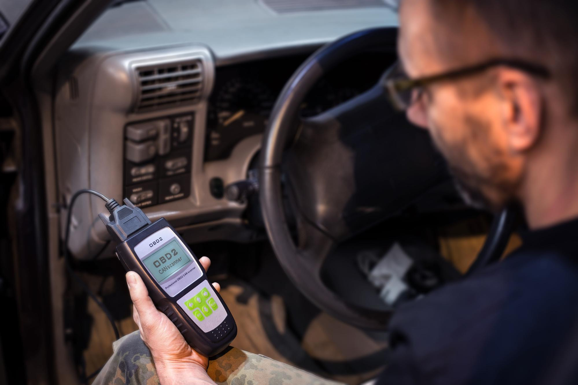 A man extracting vehicle data from an OBDII port