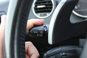 Driver activating car turn signal lever to indicate intention to turn.