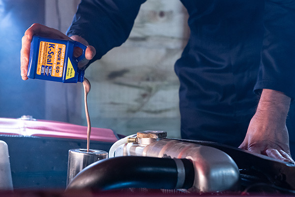 Pouring K-Seal into a car radiator, demonstrating a DIY solution for minor leaks and preventative maintenance.