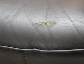 Damaged leather car seat with a noticeable scratch