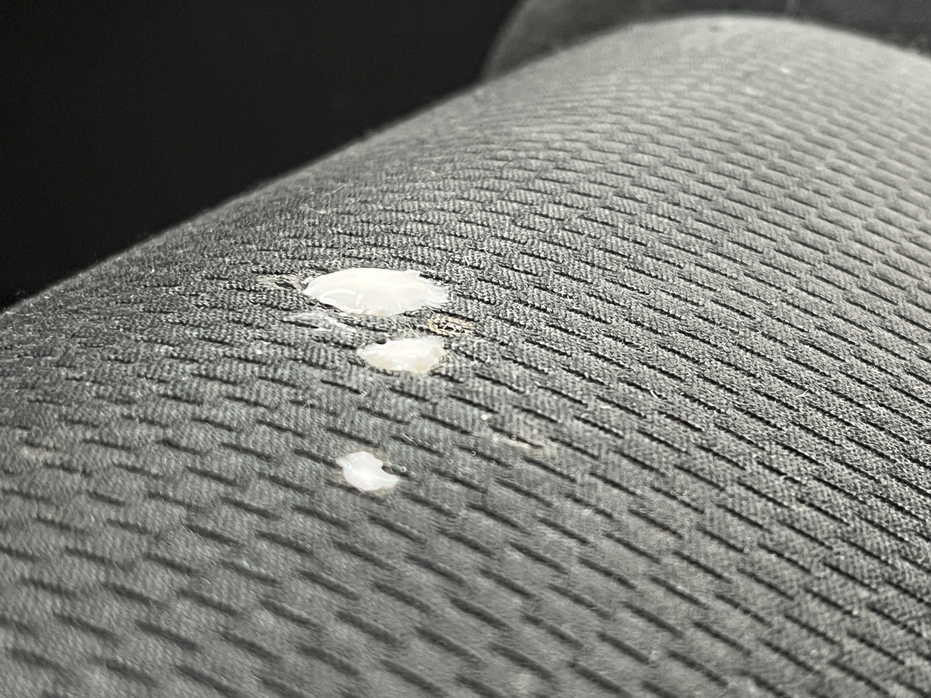 Close-up of repaired burn hole in car seat fabric