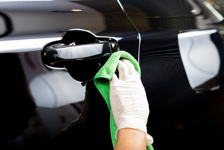 Applying pre-wax cleaner to remove old car wax, a crucial step in fixing a bad wax job.