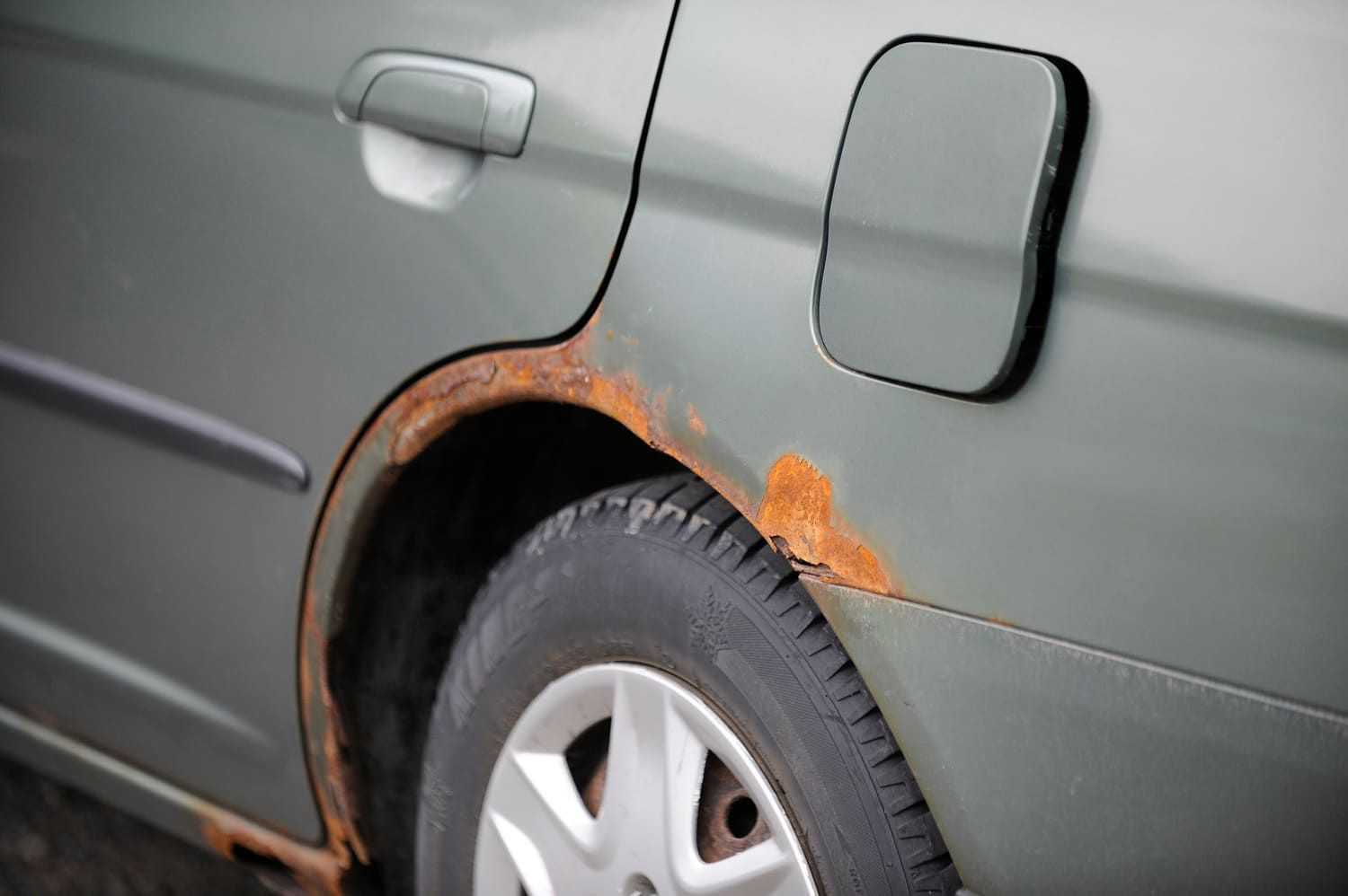 Rust damage above the wheel arch of a car, highlighting a common area for corrosion due to road debris and moisture accumulation.