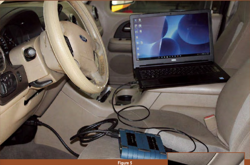 Connecting a J2534 pass-thru device to a car's OBD-II port and a laptop, illustrating the hardware setup for DIY car computer programming with a budget-friendly tool.